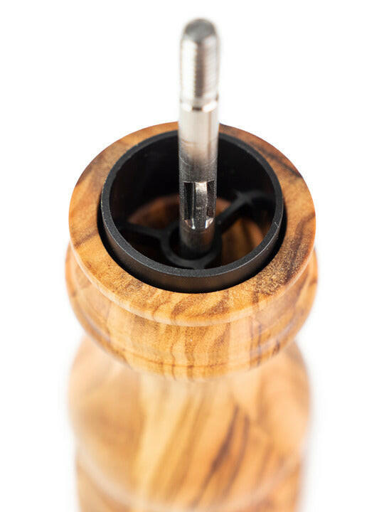 Peugeot Paris Classic Olive Salt Mill, showcasing its internal metal spindle and plastic burr-holder mechanism in a close-up view, made from sustainably sourced olive wood.