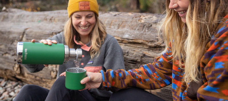 A person holding the Klean Kanteen 25oz Insulated Thermos with Built-In Cup and Pourer, ideal for versatile beverage needs during outdoor adventures.