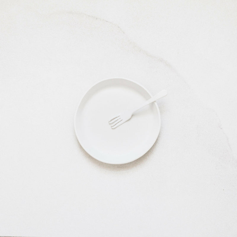 Plain white plate and fork from the Looks Like White ceramics collection by Trudy Crane, showcasing simplicity and organic design, perfect for enhancing dining experiences.