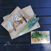 J.K. Adams | Maple Reversible Prep Boards - 16 x 12 showcasing meal prep versatility with carved poultry, grilled greens, and a whole leek on a dark wooden surface.