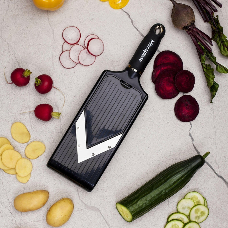 Microplane Adjustable V-Blade Mandoline Slicer with fresh sliced vegetables, showcasing its ergonomic handle and stainless steel blade for precise, effortless kitchen prep.