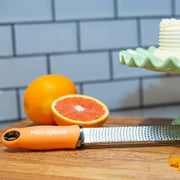 Microplane | Premium Zester, Grater - Classic Blue on cutting board with citrus, showcasing its sharp, precise blades ideal for zesting and grating in any kitchen.